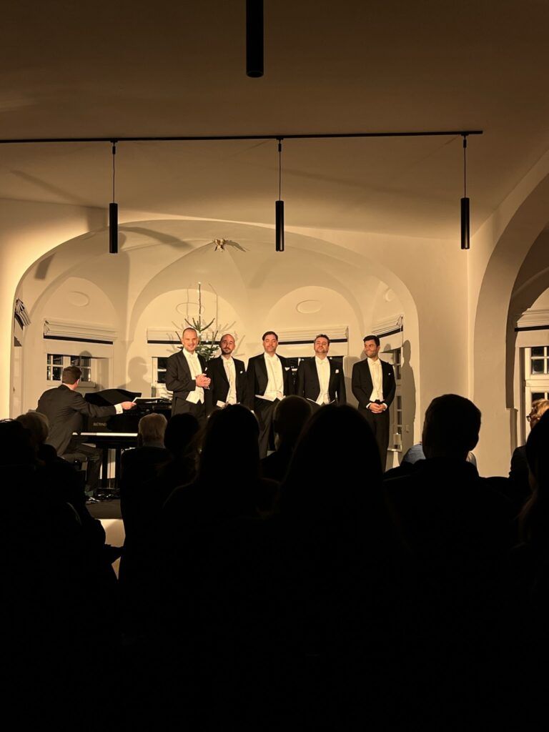 Fünf Sänger im Frack stehen nebeneinander auf der Bühne und singen